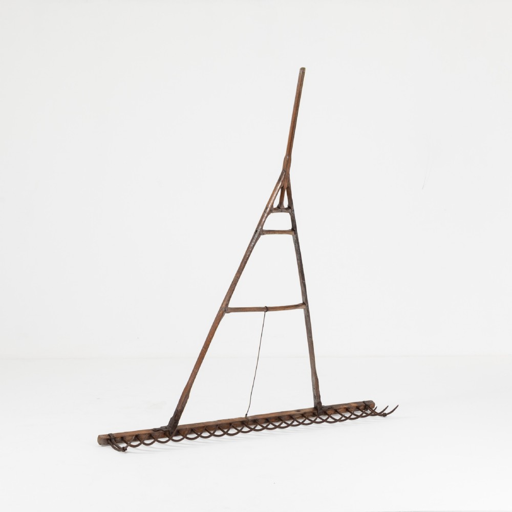 A late nineteenth-century ash hay rake featuring an elongated split-shaft handle and a wide timber head with curved tines. View II