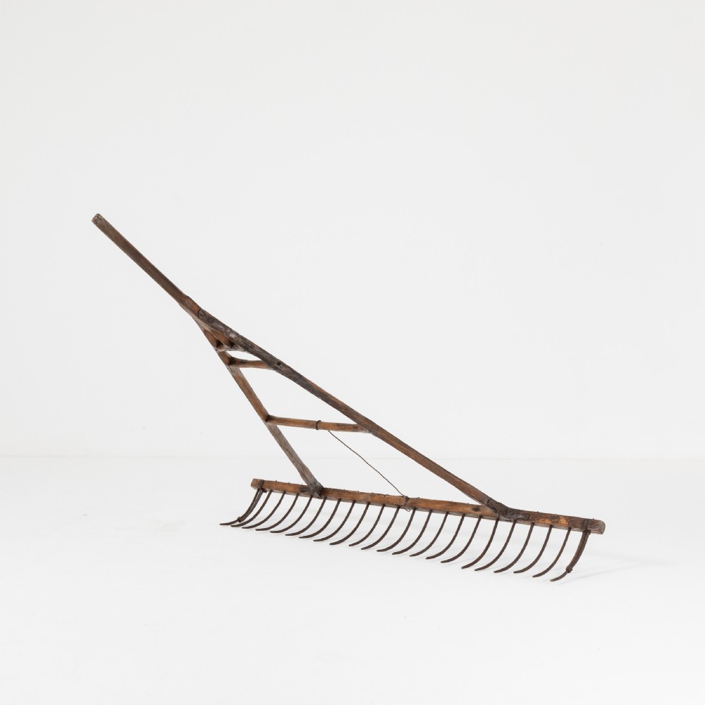 A late nineteenth-century ash hay rake featuring an elongated split-shaft handle and a wide timber head with curved tines. View III