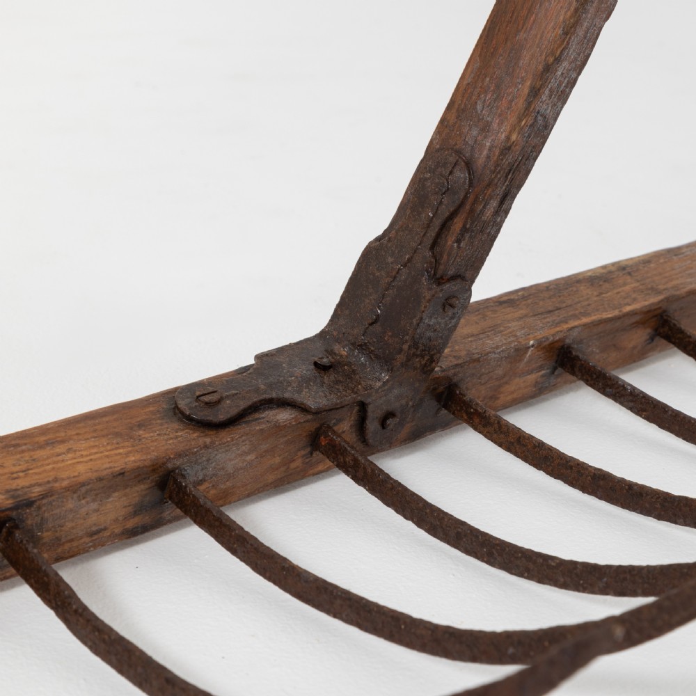 A late nineteenth-century ash hay rake featuring an elongated split-shaft handle and a wide timber head with curved tines. View VIII