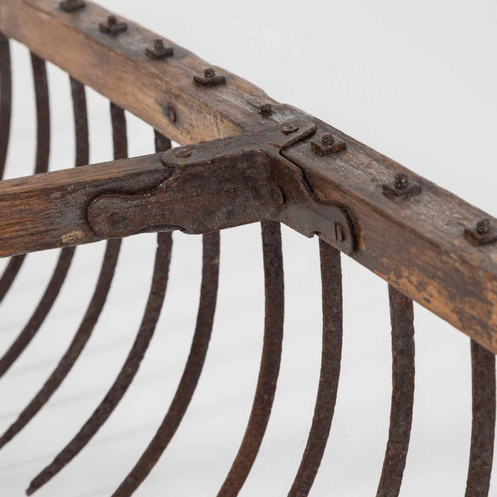 A late nineteenth-century ash hay rake featuring an elongated split-shaft handle and a wide timber head with curved tines. View IX
