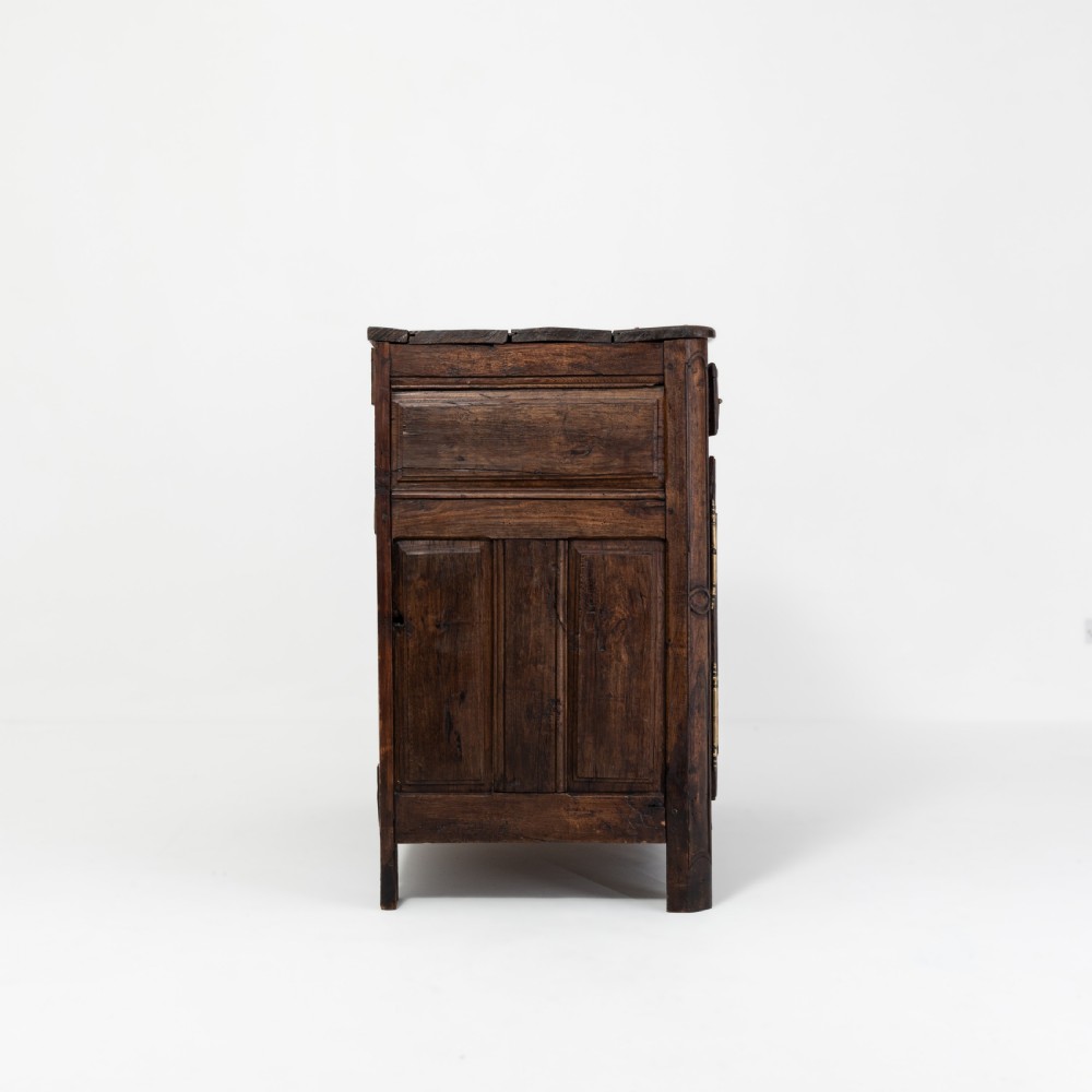 An eighteenth-century Louis XV period dark oak buffet featuring two panelled cabinet doors, three upper drawers, ornate brass hardware, and a shaped apron. View IV