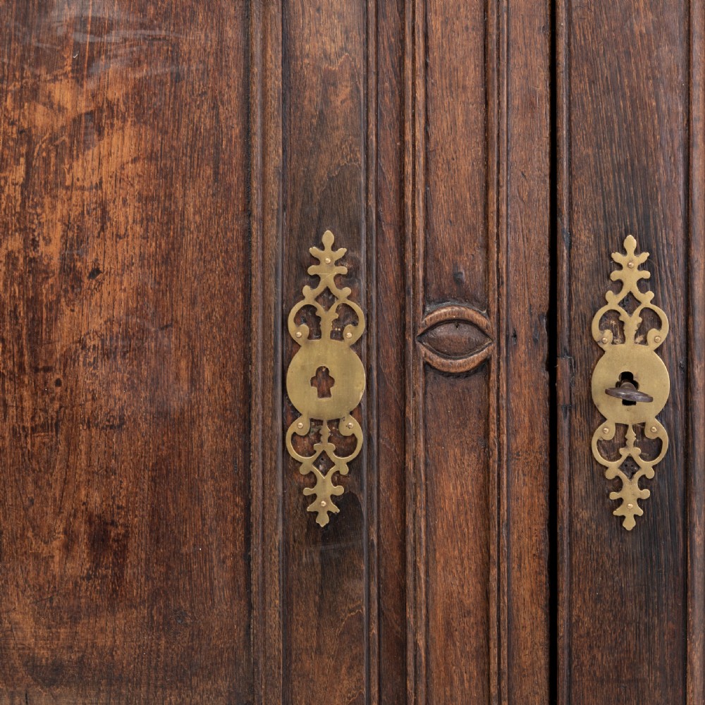 An eighteenth-century Louis XV period dark oak buffet featuring two panelled cabinet doors, three upper drawers, ornate brass hardware, and a shaped apron. View VII