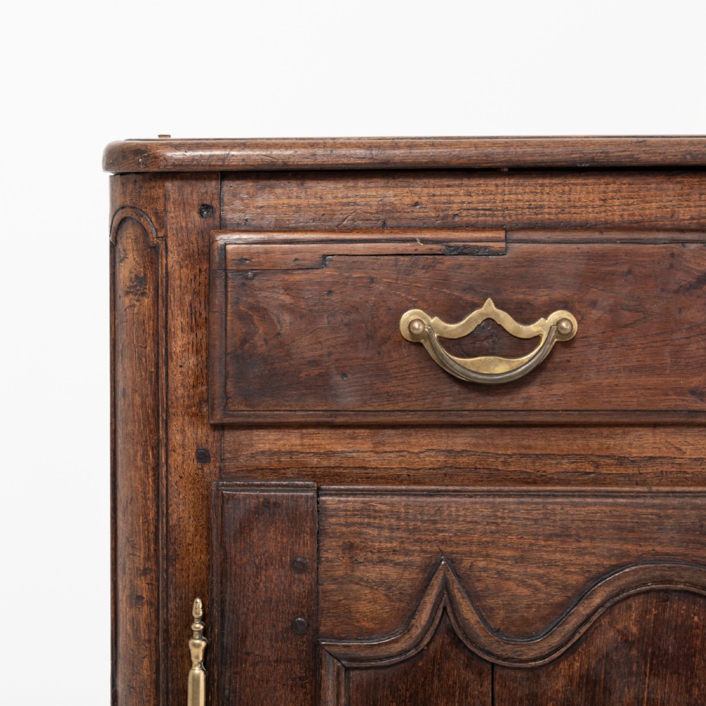 An eighteenth-century Louis XV period dark oak buffet featuring two panelled cabinet doors, three upper drawers, ornate brass hardware, and a shaped apron. View VIII