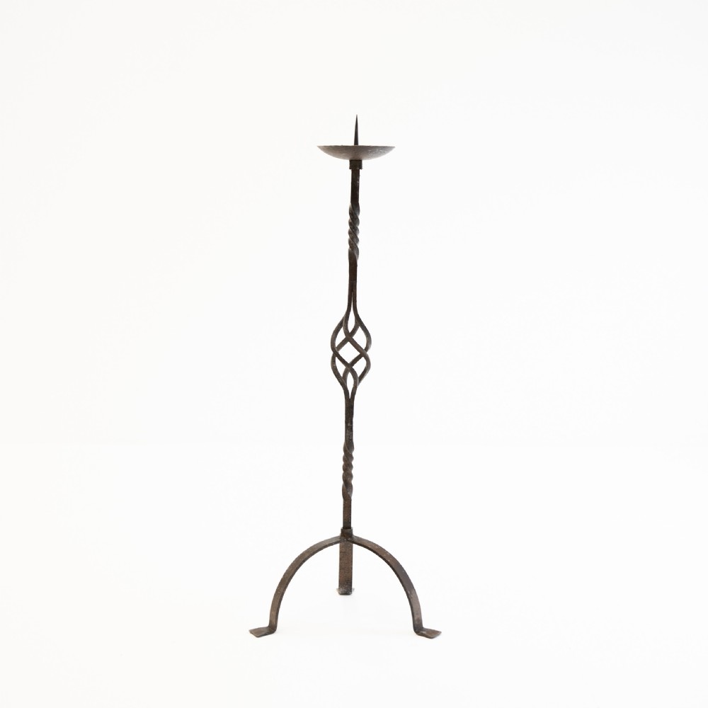 A 19th-century wrought iron pricket candlestick featuring a central spike, twisted stem section, cage knop detail, and an arched tripod base.