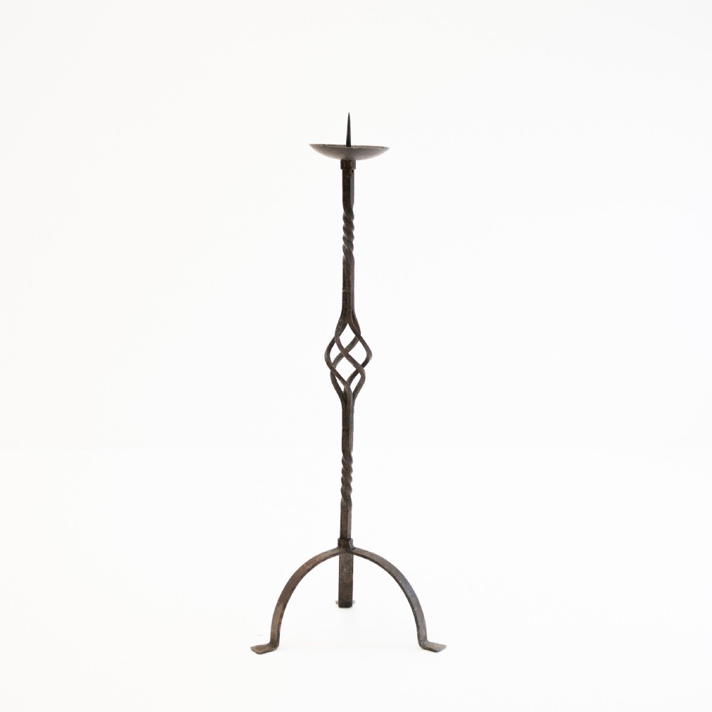 A 19th-century wrought iron pricket candlestick featuring a central spike, twisted stem section, cage knop detail, and an arched tripod base. View V