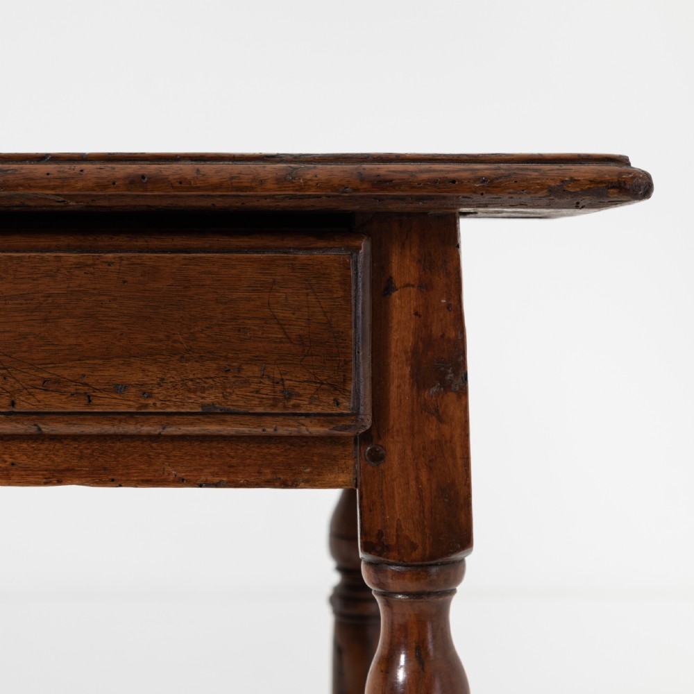 A 17th-century Welsh oak tavern table with turned legs, a single drawer, and an H-stretcher base. View V