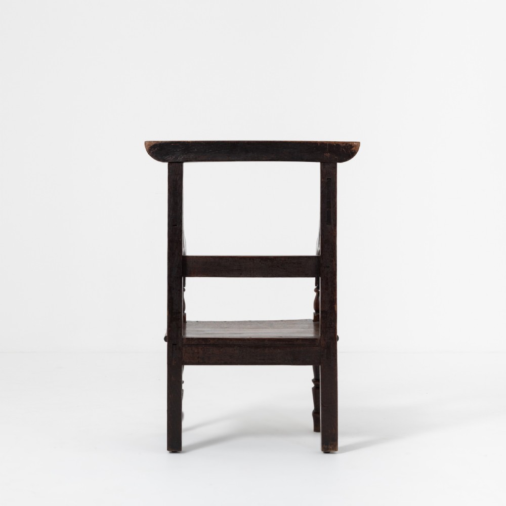 A dark brown 19th-century oak and elm armchair featuring turned front legs, curved arm supports, and a flat top crest rail. View III