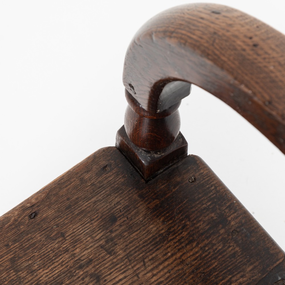 A dark brown 19th-century oak and elm armchair featuring turned front legs, curved arm supports, and a flat top crest rail. View X