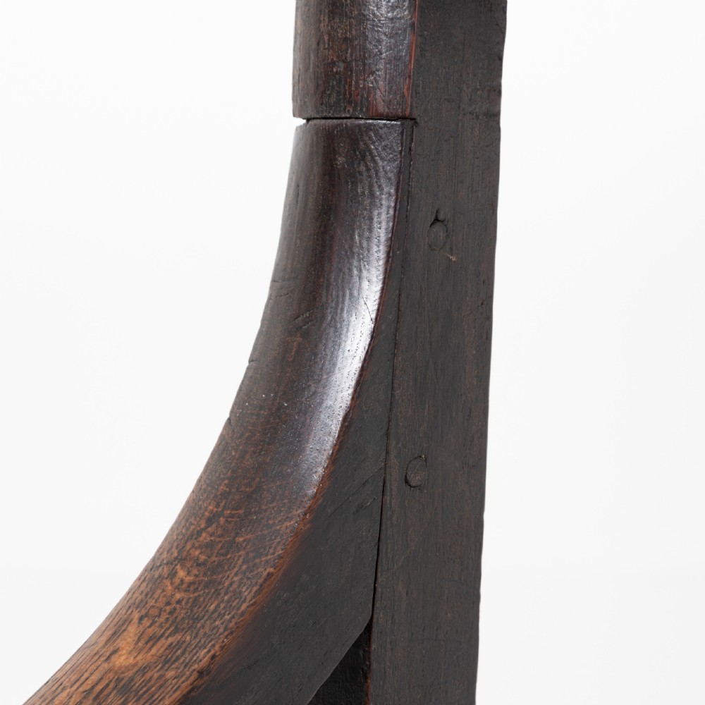 A dark brown 19th-century oak and elm armchair featuring turned front legs, curved arm supports, and a flat top crest rail. View XII