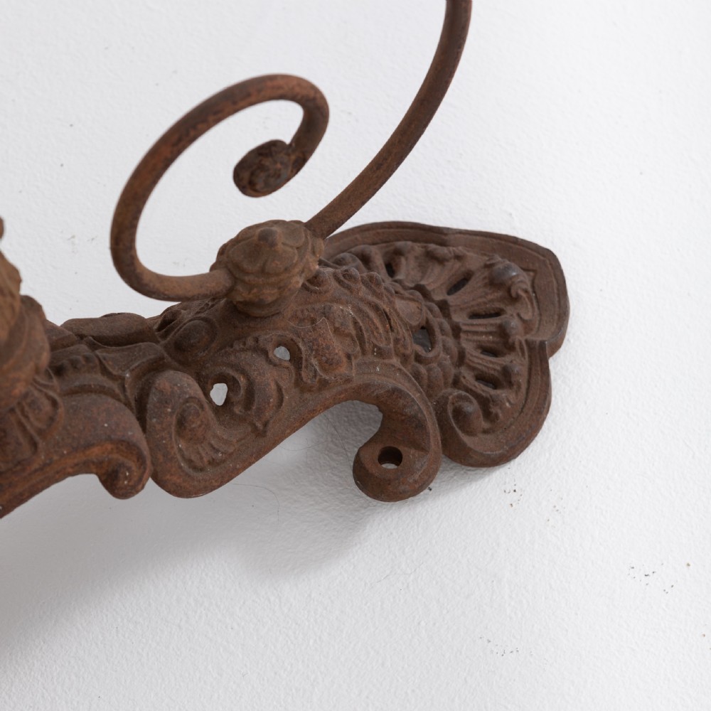 Victorian cast iron freestanding child swing featuring scrolled feet, brass finials, and a red fabric-upholstered suspended seat. View VIII