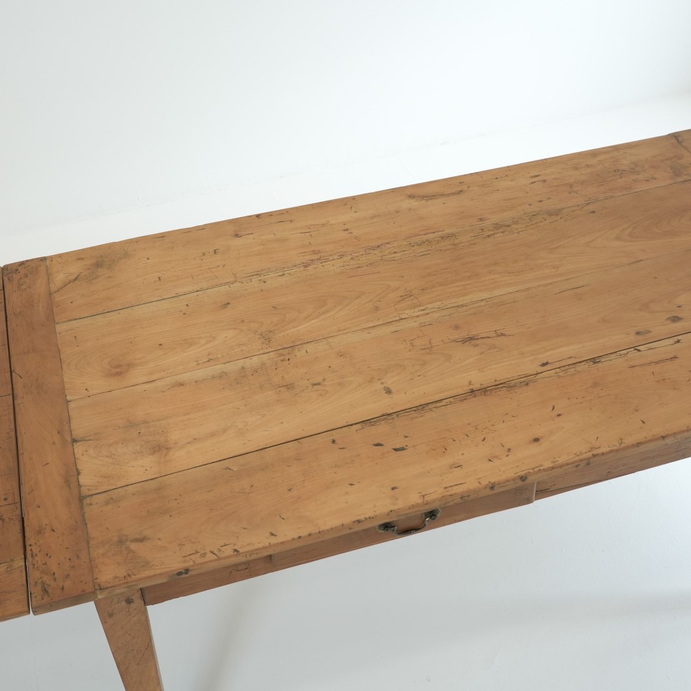 A nineteenth-century French provincial fruitwood dining table featuring square tapered legs, a single frieze drawer, and a draw-leaf extension system. View IX