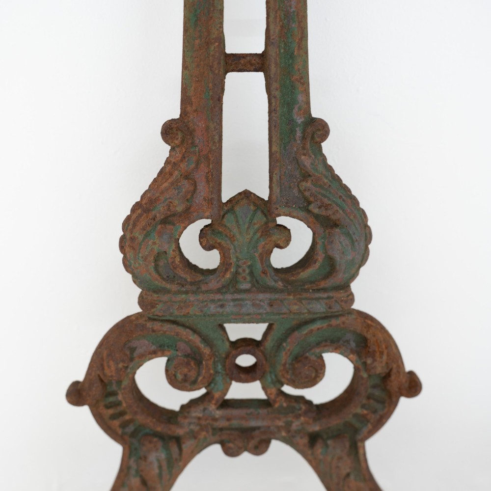 A pair of ornate Victorian cast iron table bases featuring openwork scrollwork and a rusted finish with traces of original green paint. View V
