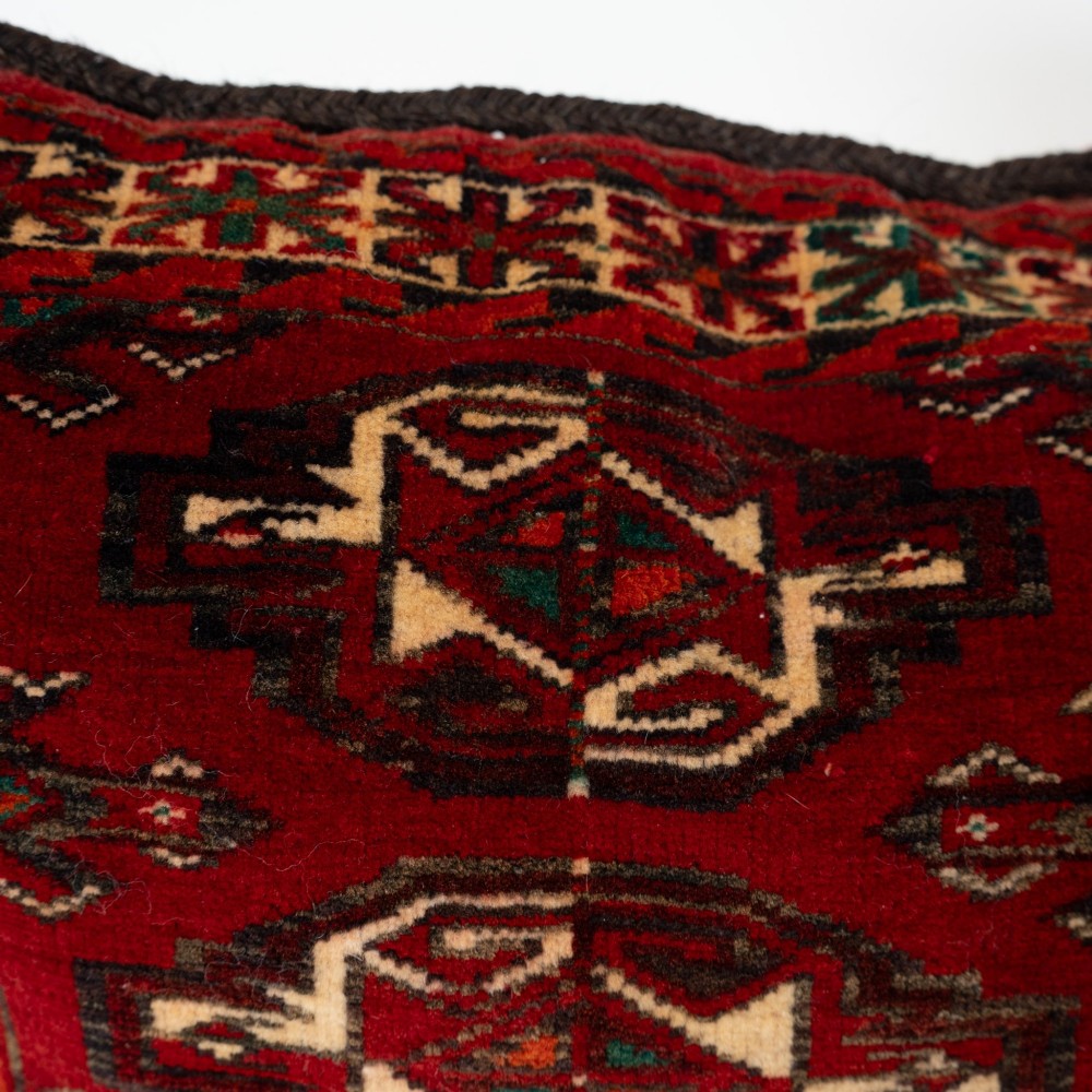 A rectangular hand-woven wool cushion featuring geometric Turkmen gul patterns in deep red, cream, and dark brown. View VI