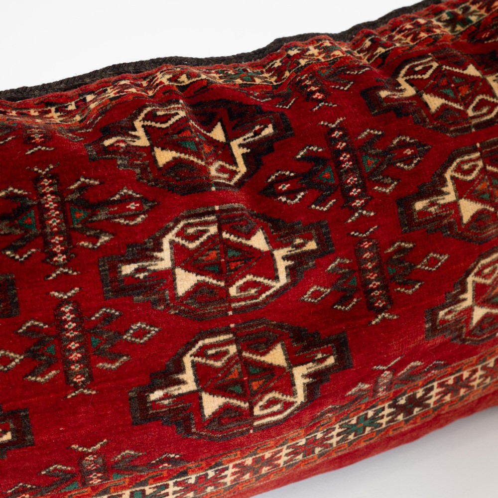 A rectangular hand-woven wool cushion featuring geometric Turkmen gul patterns in deep red, cream, and dark brown. View VII