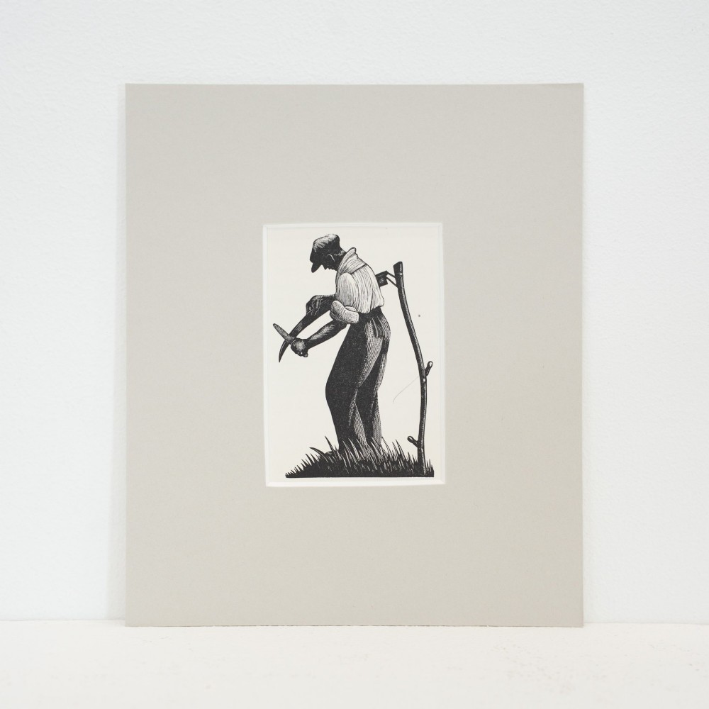 A monochrome wood engraving depicting a figure sharpening a scythe outdoors, presented within a wide neutral card mount.