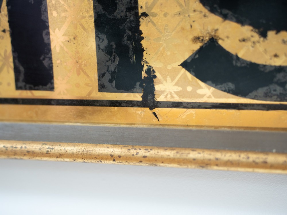 A long rectangular late Victorian verre eglomise glass shop sign framed in gold timber, displaying bold black lettering reading CHEMIST & on a gilded background. View VI