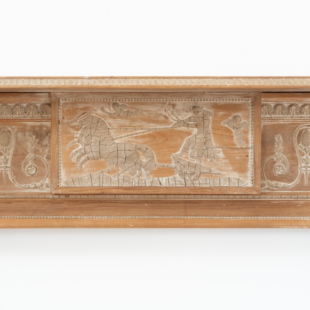 A Victorian stripped pine fireplace surround featuring fluted side columns, a stepped mantel shelf, and a central carved panel depicting a chariot scene. View III