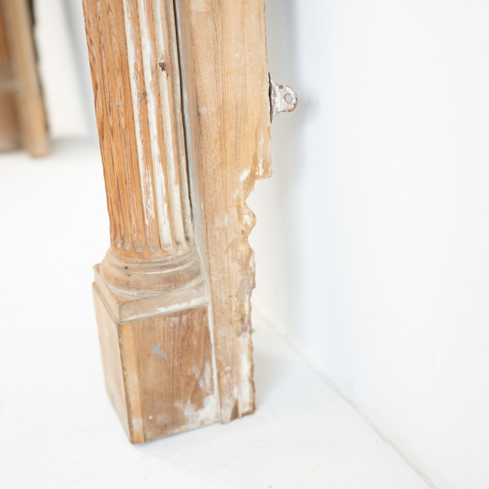 A Victorian stripped pine fireplace surround featuring fluted side columns, a stepped mantel shelf, and a central carved panel depicting a chariot scene. View VII
