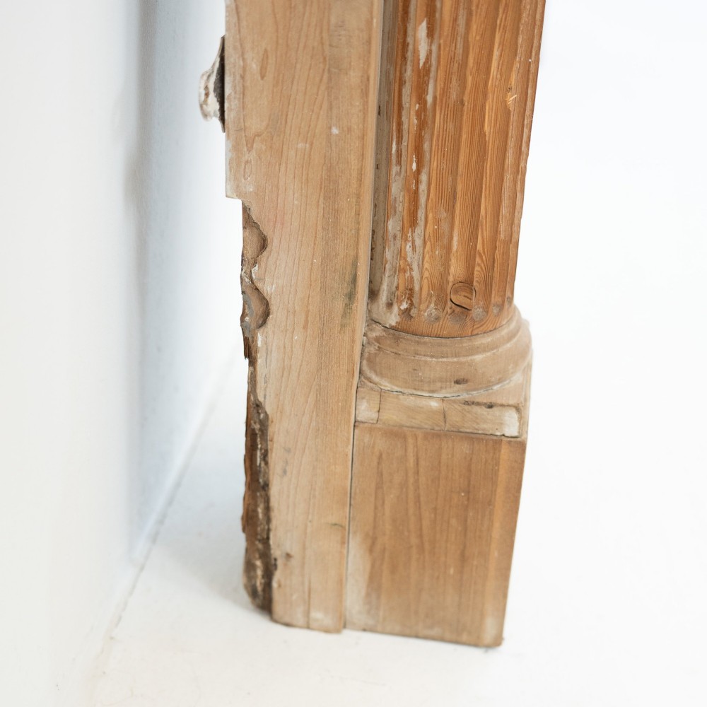 A Victorian stripped pine fireplace surround featuring fluted side columns, a stepped mantel shelf, and a central carved panel depicting a chariot scene. View VIII