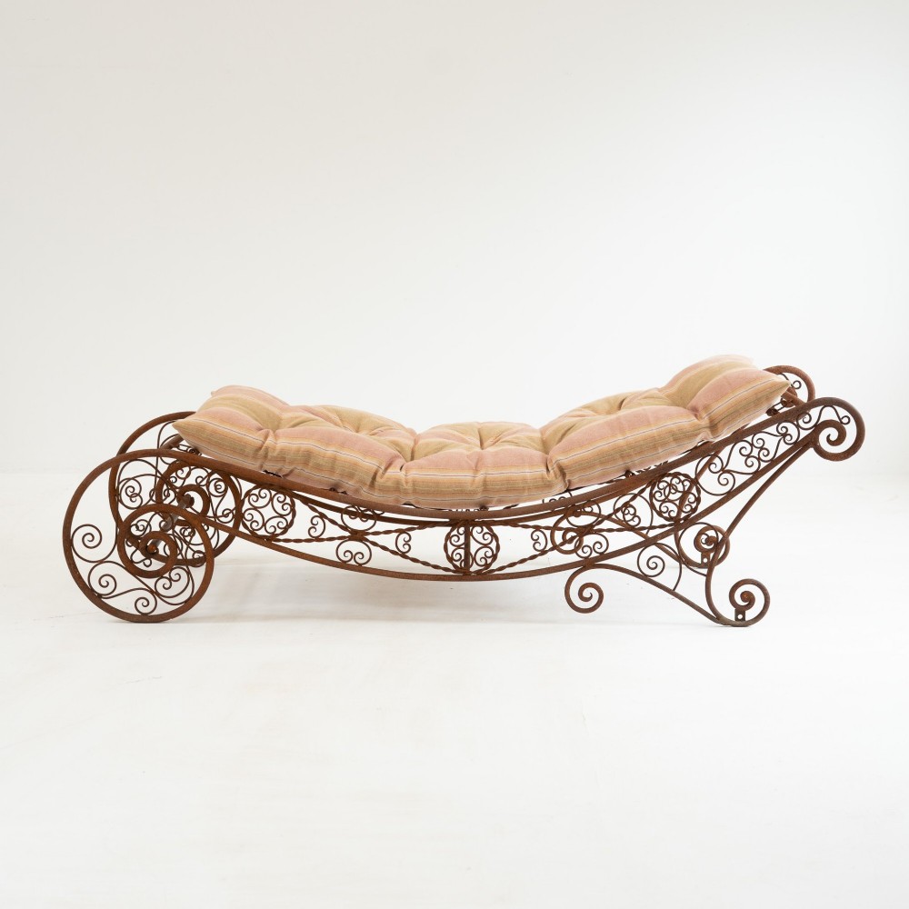 A nineteenth-century French wrought iron garden daybed featuring scrollwork, a contoured reclining frame, and decorative front wheels with a weathered brown patina. View IV