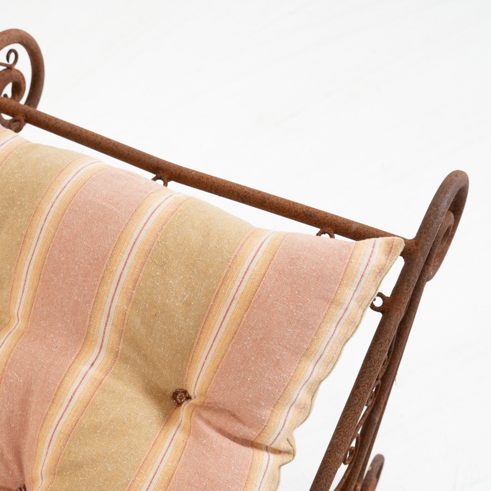 A nineteenth-century French wrought iron garden daybed featuring scrollwork, a contoured reclining frame, and decorative front wheels with a weathered brown patina. View VI