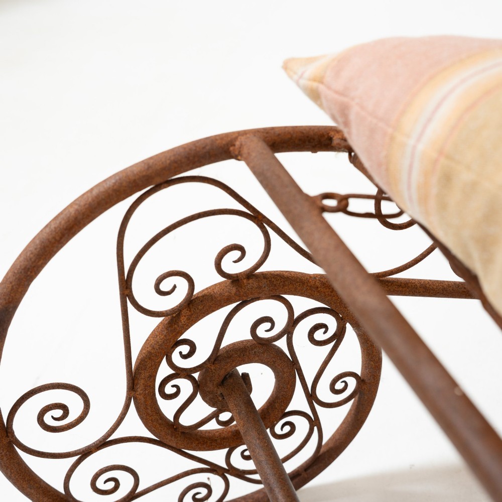 A nineteenth-century French wrought iron garden daybed featuring scrollwork, a contoured reclining frame, and decorative front wheels with a weathered brown patina. View VII