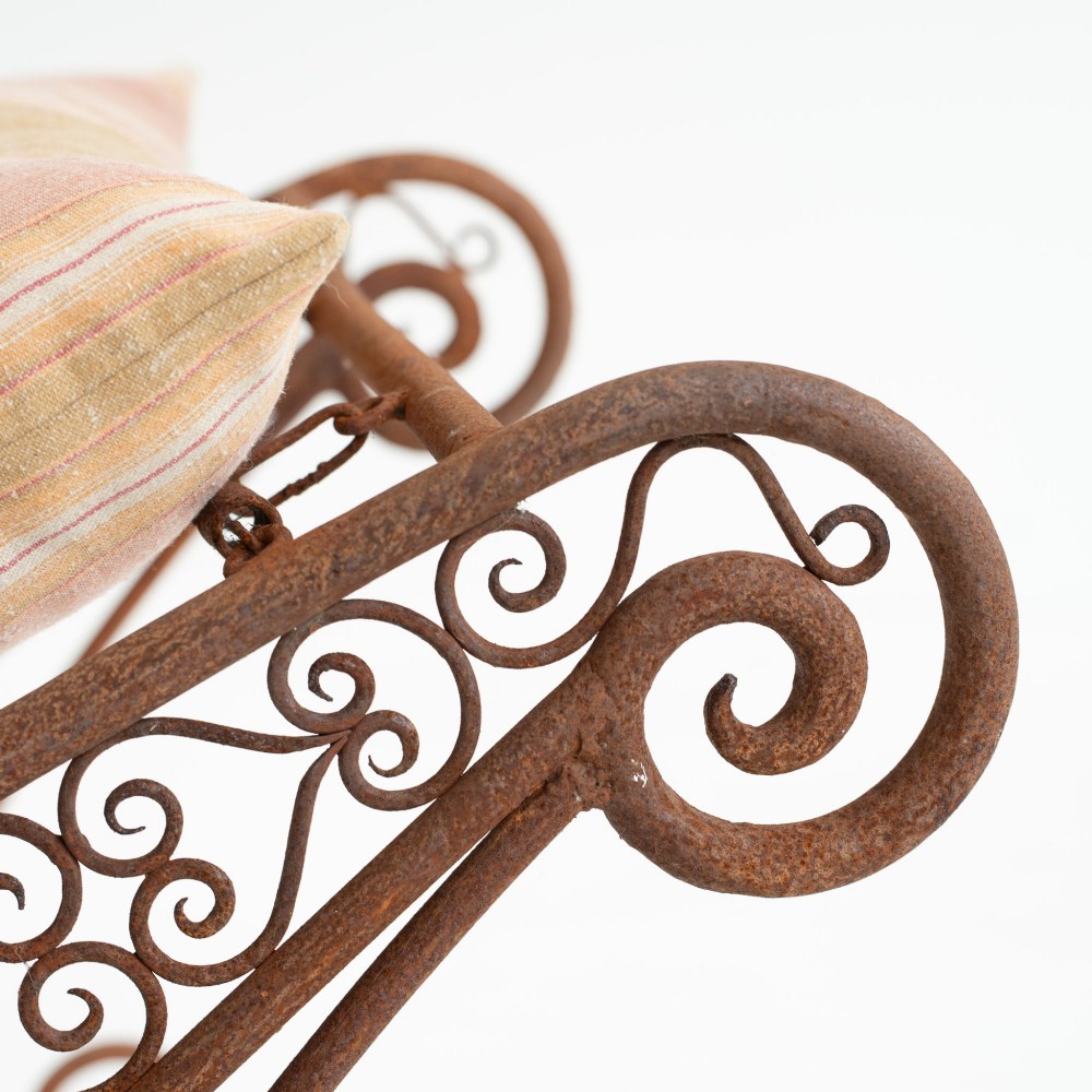 A nineteenth-century French wrought iron garden daybed featuring scrollwork, a contoured reclining frame, and decorative front wheels with a weathered brown patina. View VIII