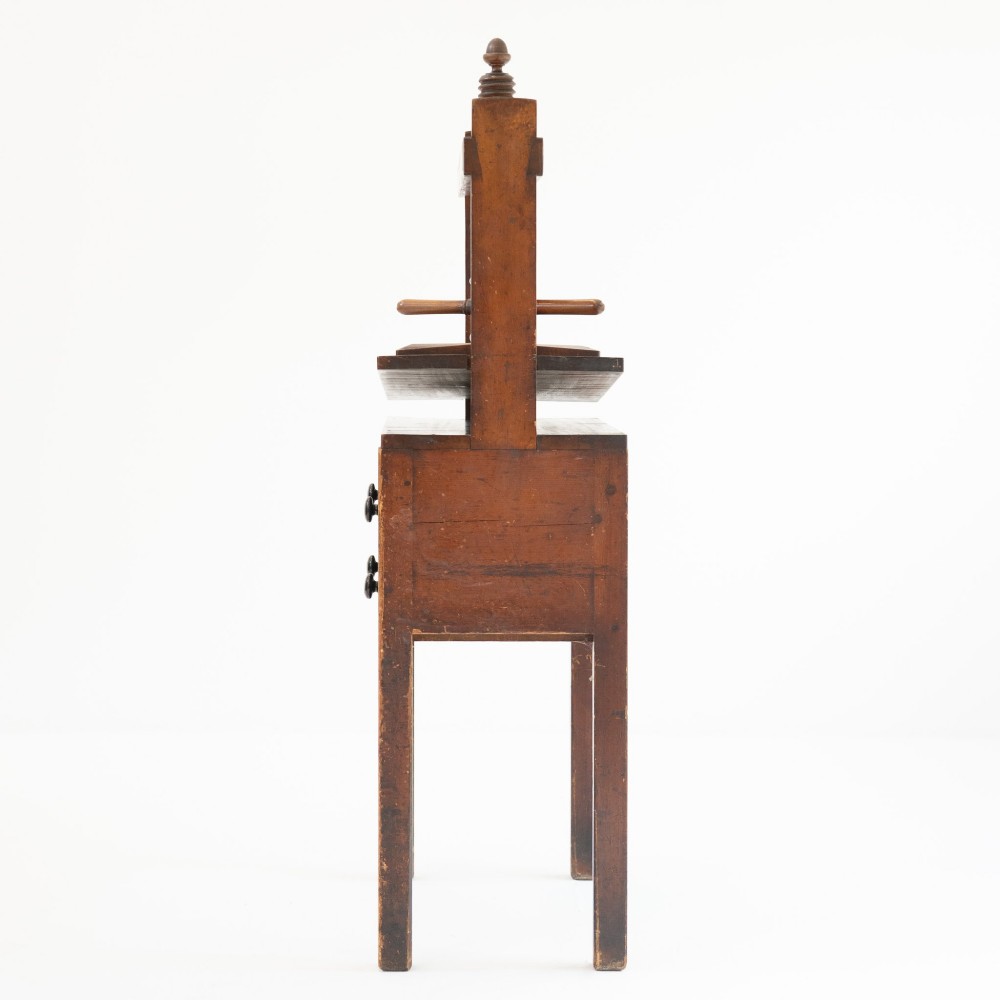 A Victorian mahogany and pine linen press featuring a central wooden screw mechanism over two small drawers with turned black knobs and four square legs. View VI