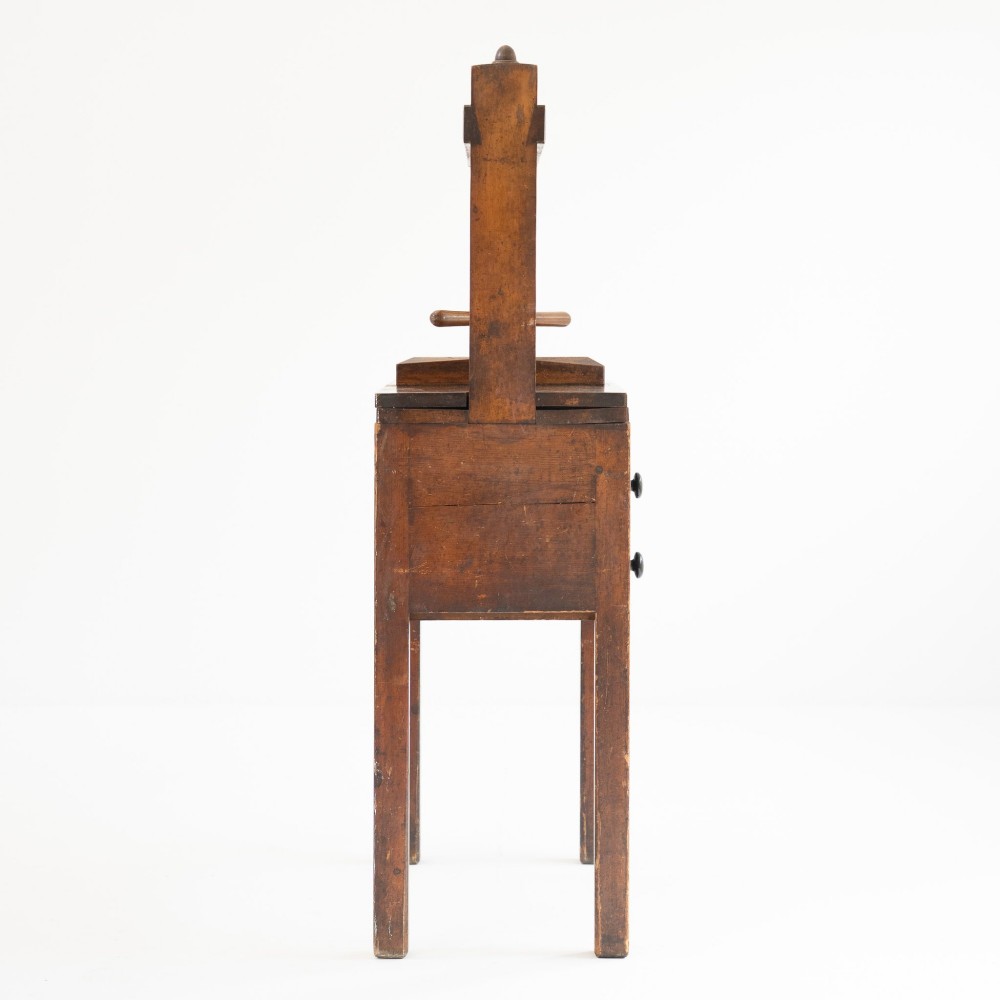A Victorian mahogany and pine linen press featuring a central wooden screw mechanism over two small drawers with turned black knobs and four square legs. View VIII