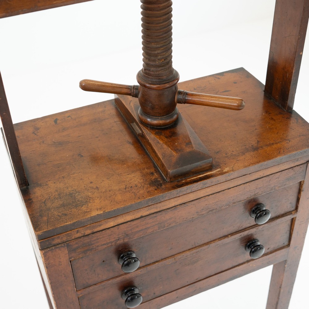 A Victorian mahogany and pine linen press featuring a central wooden screw mechanism over two small drawers with turned black knobs and four square legs. View IX