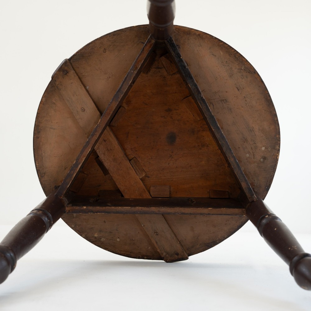A 19th-century circular pine cricket table featuring a dark painted finish and three turned legs. View V
