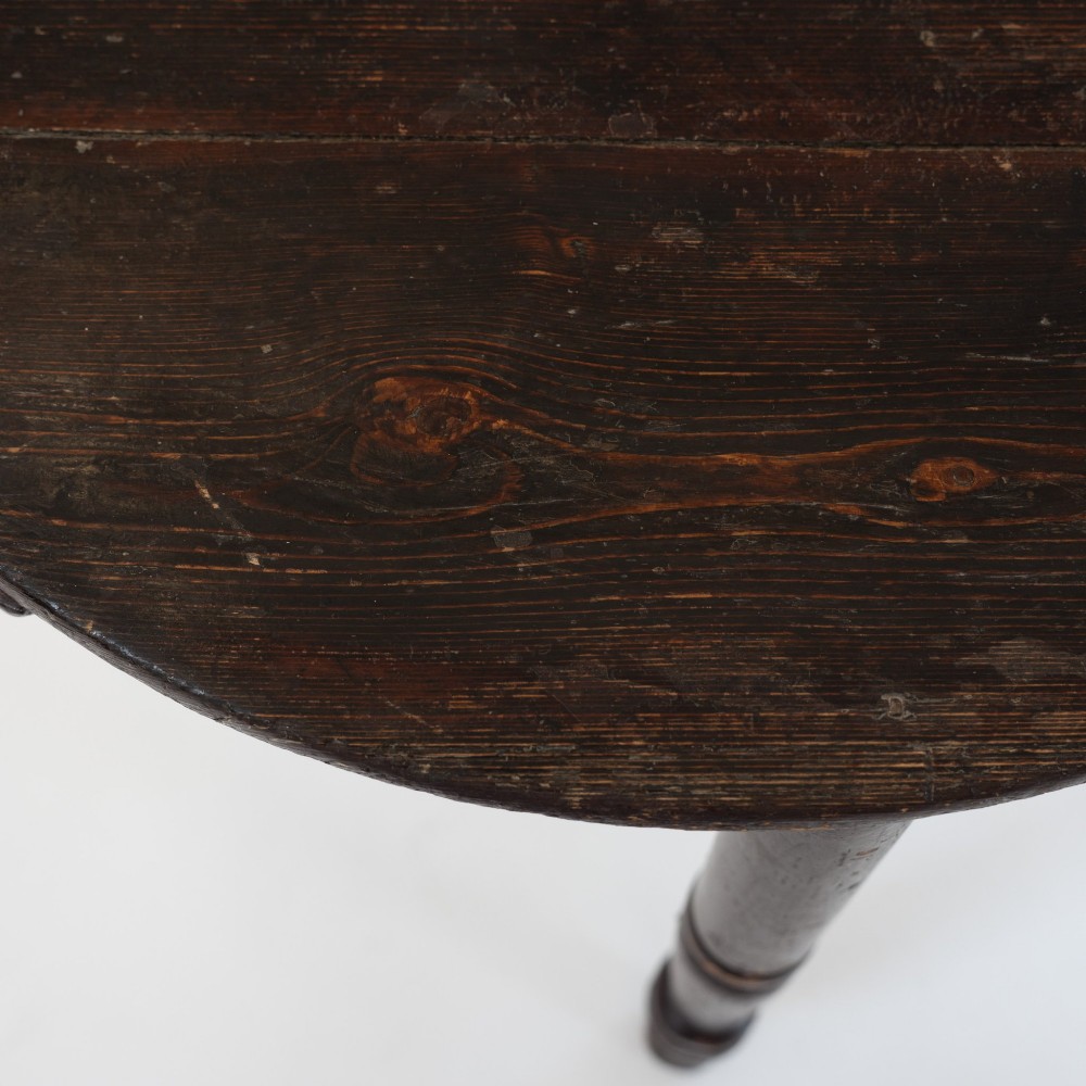 A 19th-century circular pine cricket table featuring a dark painted finish and three turned legs. View X
