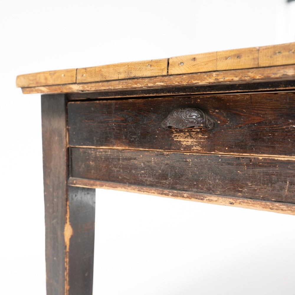 An eight-foot long Victorian pine harvest table featuring a natural timber top surface, a distressed black painted apron, and tapered square legs. View VII