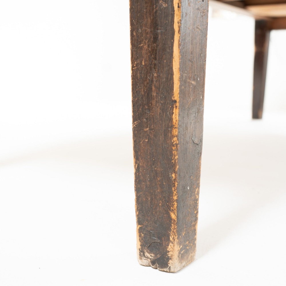 An eight-foot long Victorian pine harvest table featuring a natural timber top surface, a distressed black painted apron, and tapered square legs. View VIII
