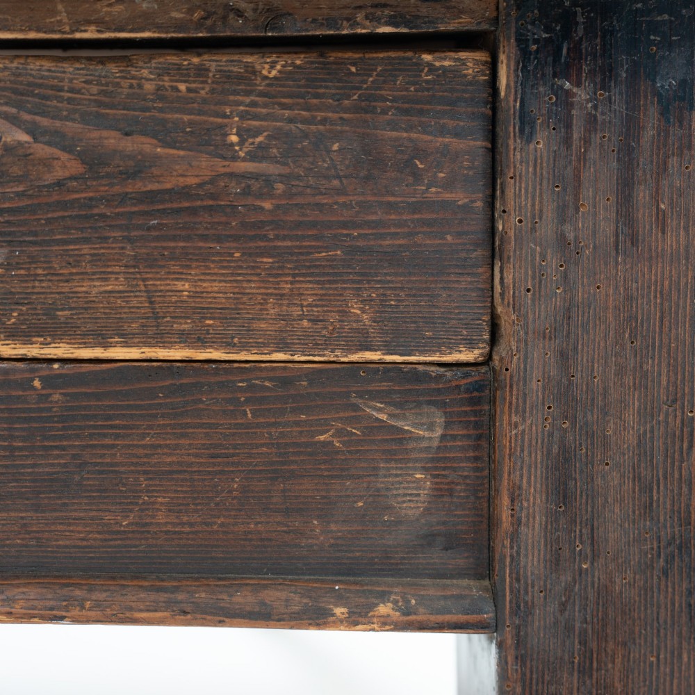 An eight-foot long Victorian pine harvest table featuring a natural timber top surface, a distressed black painted apron, and tapered square legs. View X