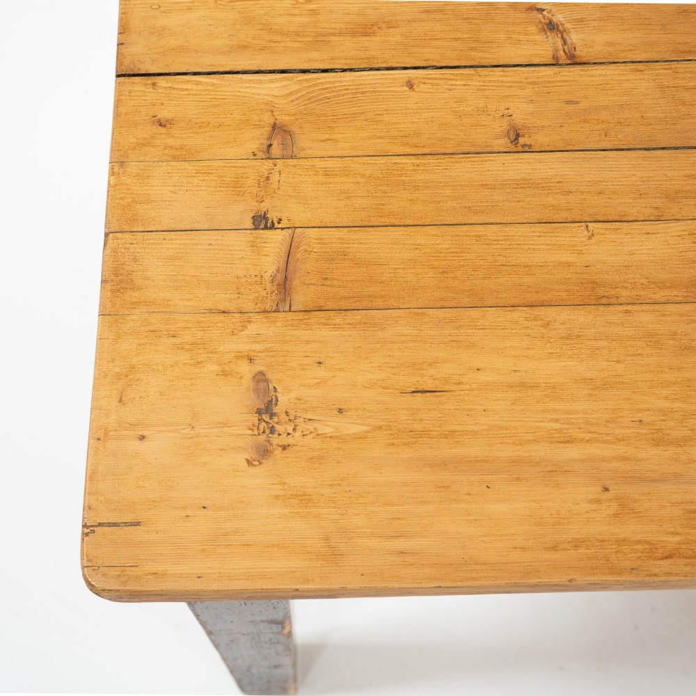 An eight-foot long Victorian pine harvest table featuring a natural timber top surface, a distressed black painted apron, and tapered square legs. View XII