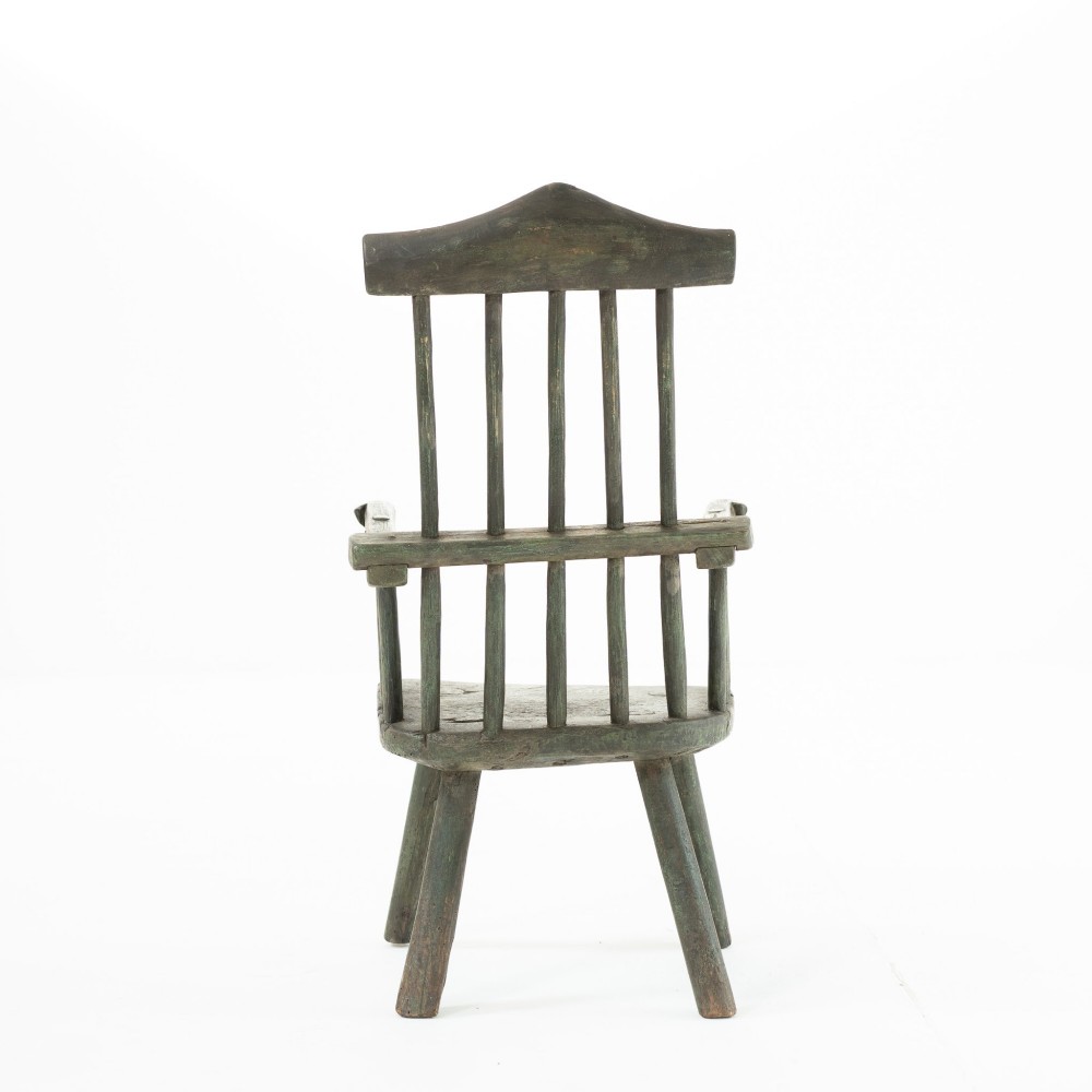 A 19th-century primitive childs stick-back armchair crafted from dark patinated timber with splayed legs and a crest rail. View IV