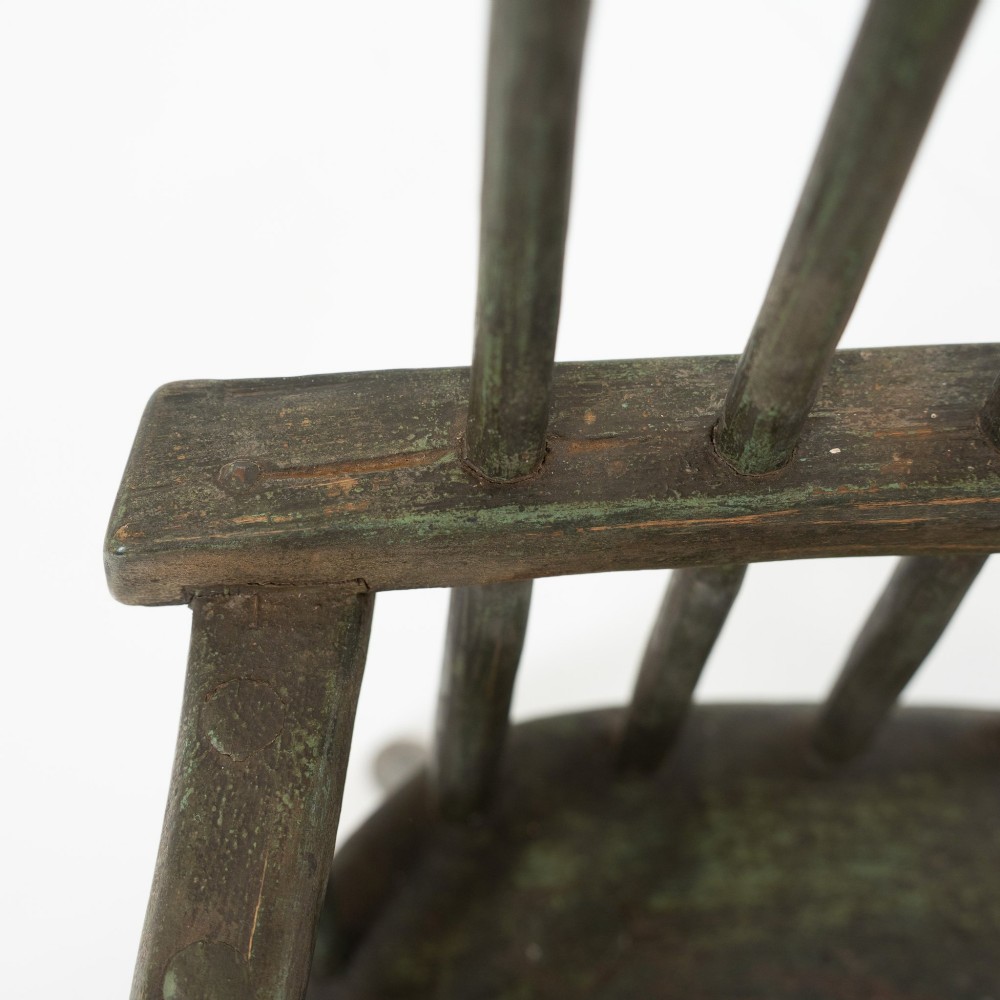 A 19th-century primitive childs stick-back armchair crafted from dark patinated timber with splayed legs and a crest rail. View VIII