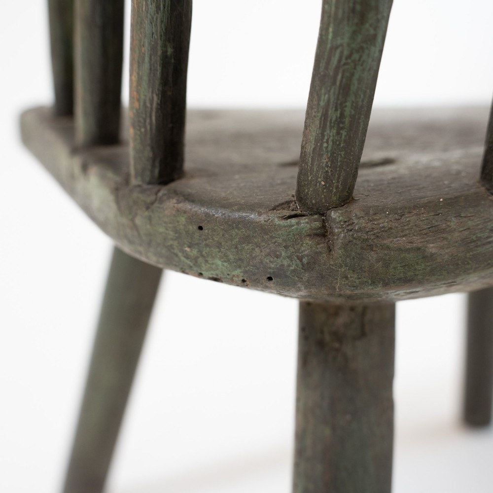 A 19th-century primitive childs stick-back armchair crafted from dark patinated timber with splayed legs and a crest rail. View XII