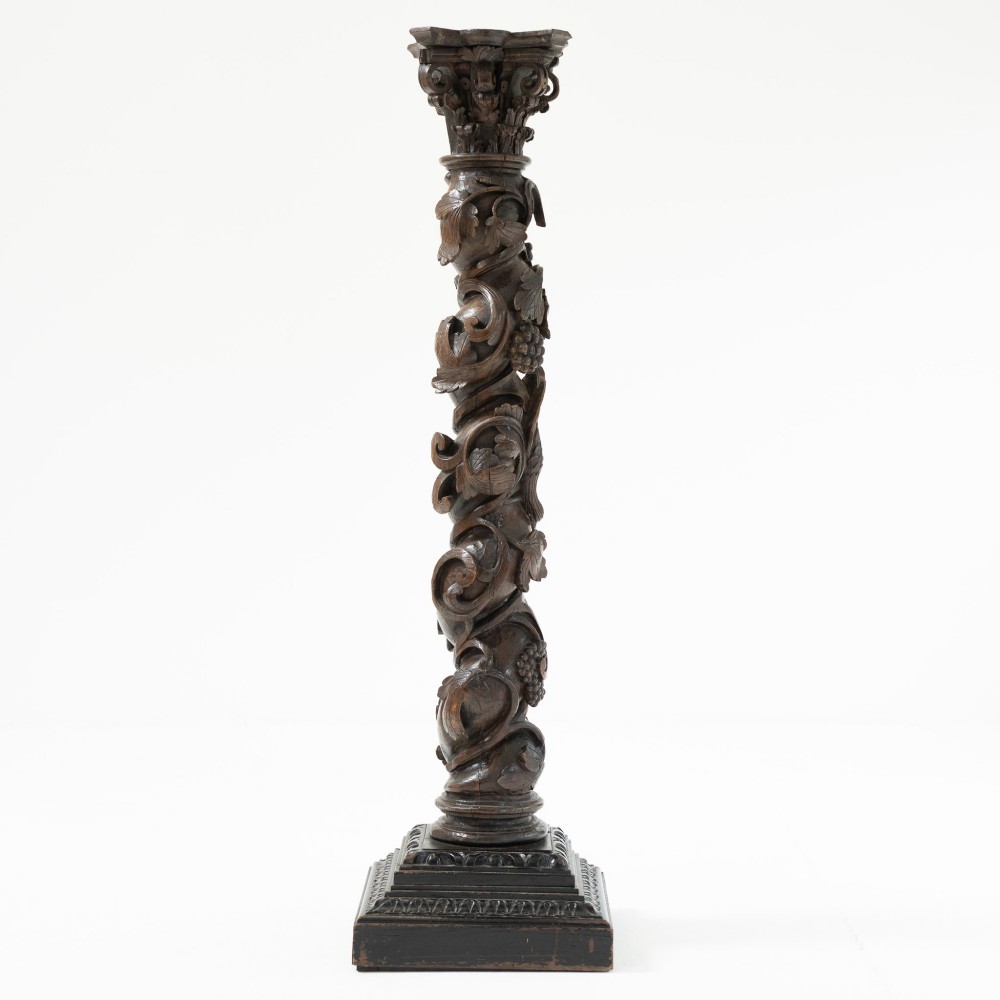 A dark carved oak Solomonic pedestal column with a spiralled grapevine shaft, Corinthian capital, and stepped square base. View II