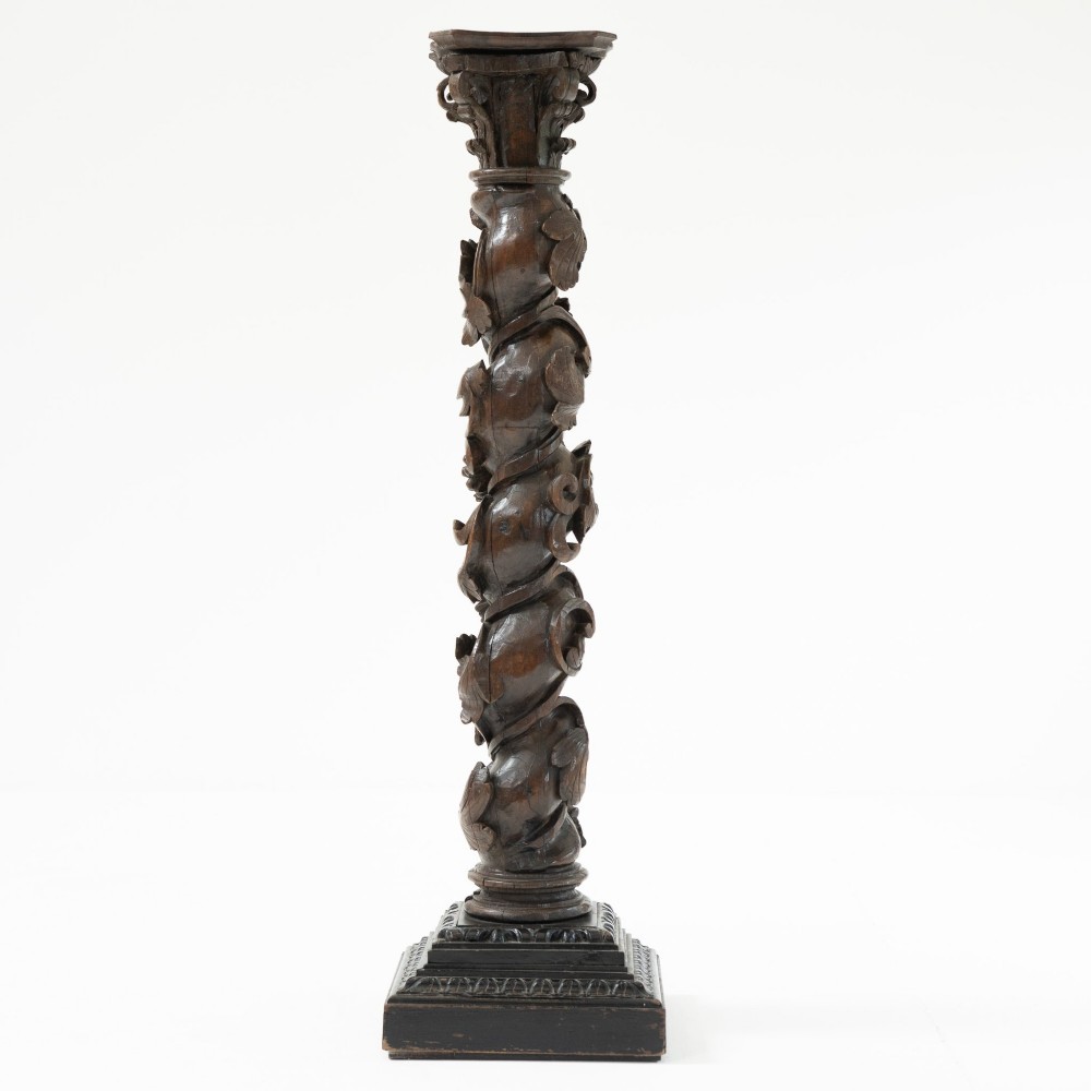 A dark carved oak Solomonic pedestal column with a spiralled grapevine shaft, Corinthian capital, and stepped square base. View III