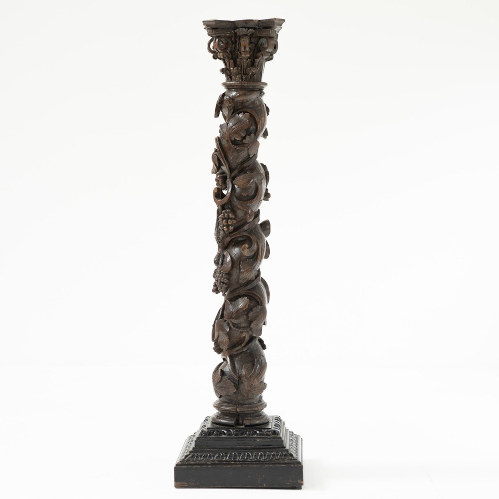 A dark carved oak Solomonic pedestal column with a spiralled grapevine shaft, Corinthian capital, and stepped square base. View IV