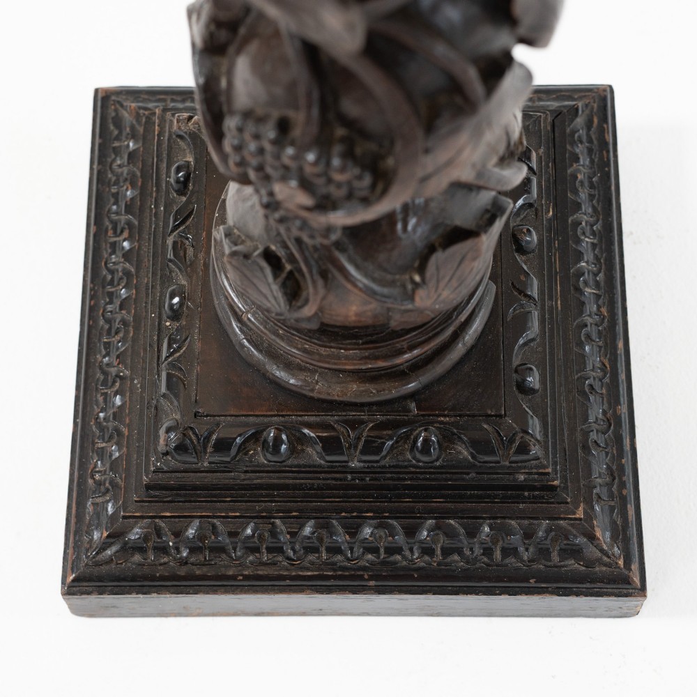 A dark carved oak Solomonic pedestal column with a spiralled grapevine shaft, Corinthian capital, and stepped square base. View VI