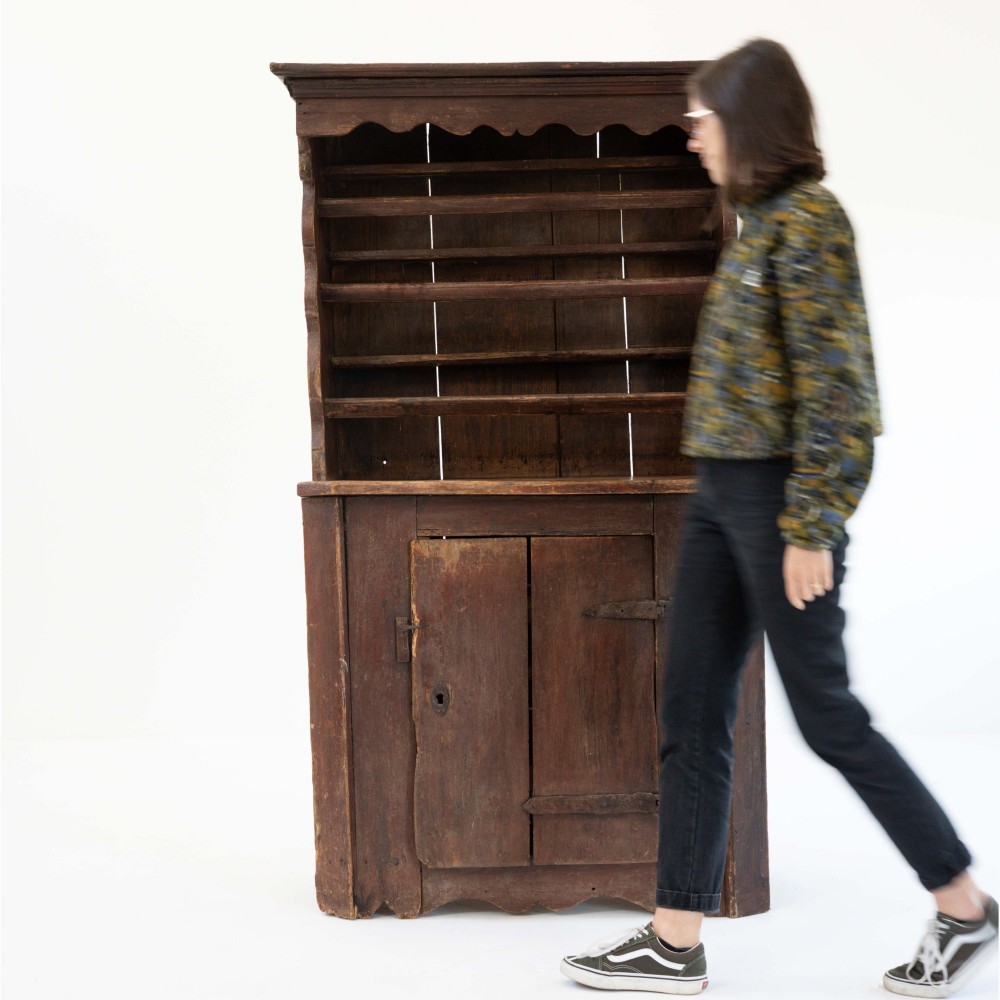 A late eighteenth-century dark timber Irish kitchen dresser featuring open plate shelves with scalloped sides above a single-door cupboard base with wrought iron hinges. View II