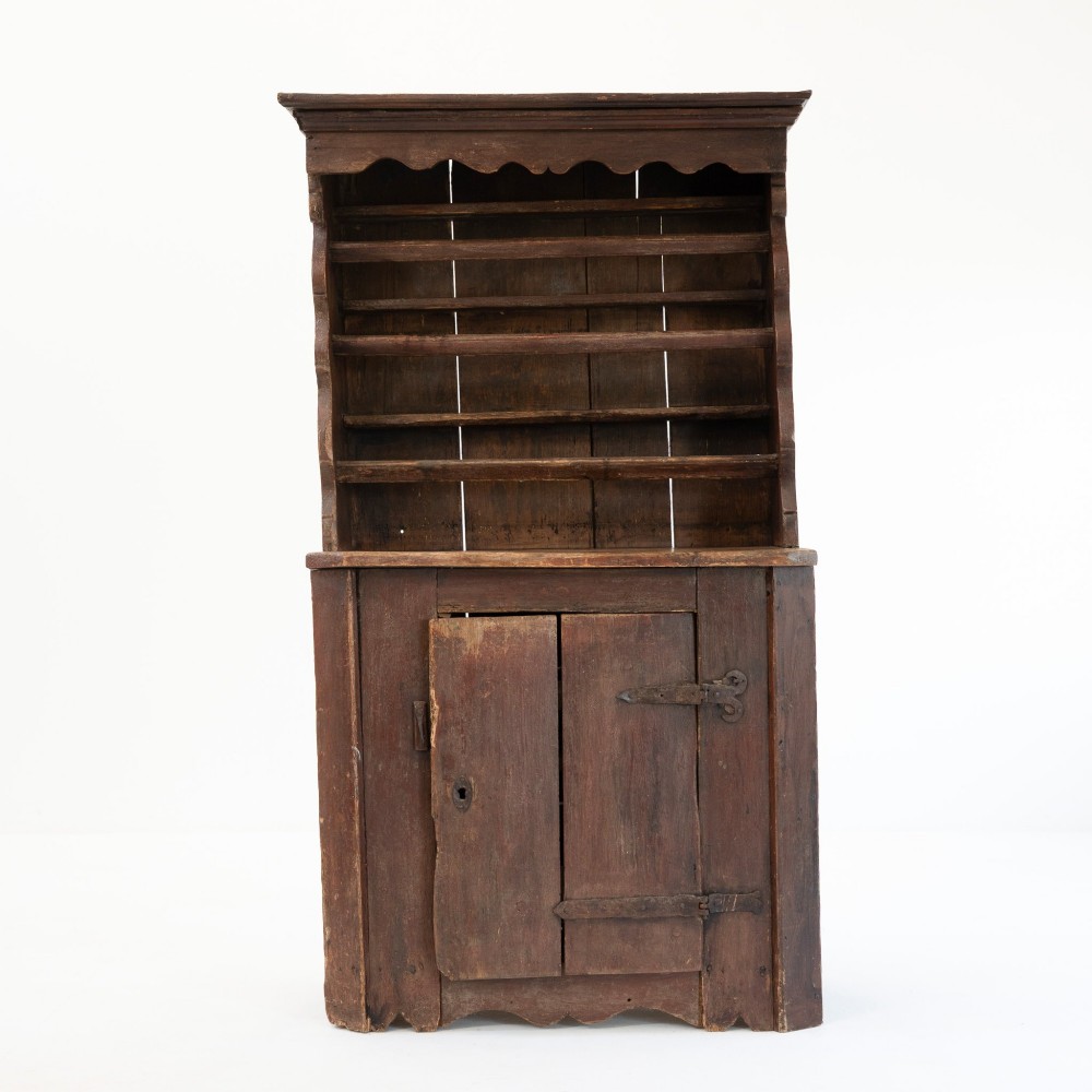 A late eighteenth-century dark timber Irish kitchen dresser featuring open plate shelves with scalloped sides above a single-door cupboard base with wrought iron hinges. View III