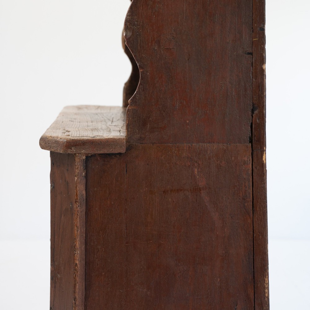 A late eighteenth-century dark timber Irish kitchen dresser featuring open plate shelves with scalloped sides above a single-door cupboard base with wrought iron hinges. View VI