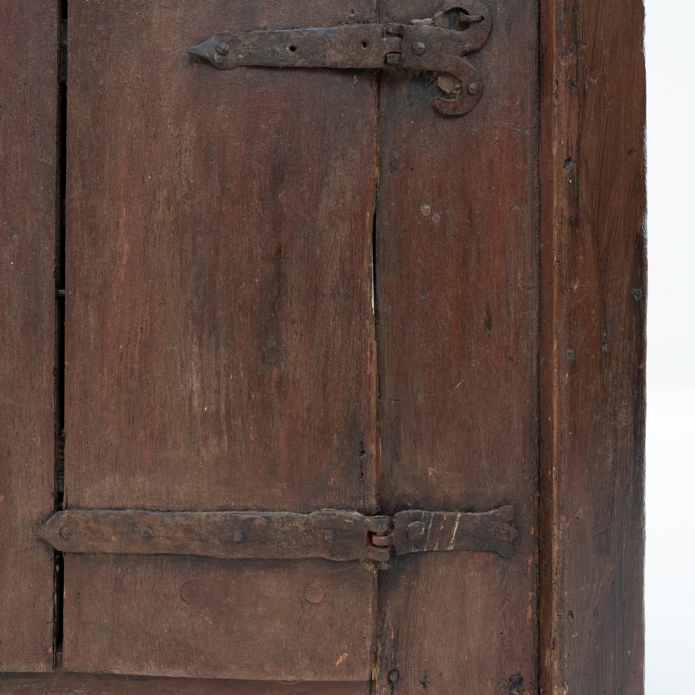 A late eighteenth-century dark timber Irish kitchen dresser featuring open plate shelves with scalloped sides above a single-door cupboard base with wrought iron hinges. View XI