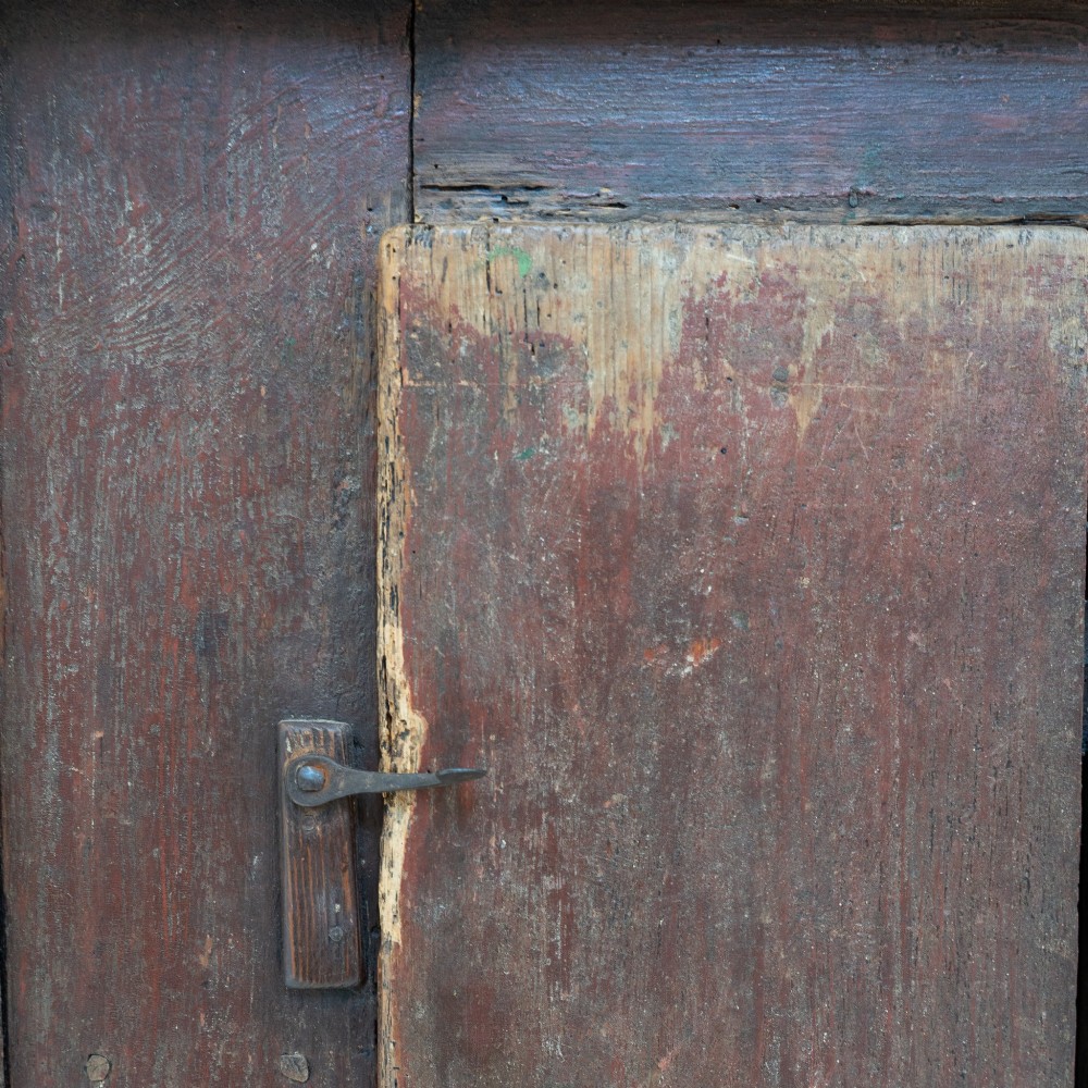 A late eighteenth-century dark timber Irish kitchen dresser featuring open plate shelves with scalloped sides above a single-door cupboard base with wrought iron hinges. View XII