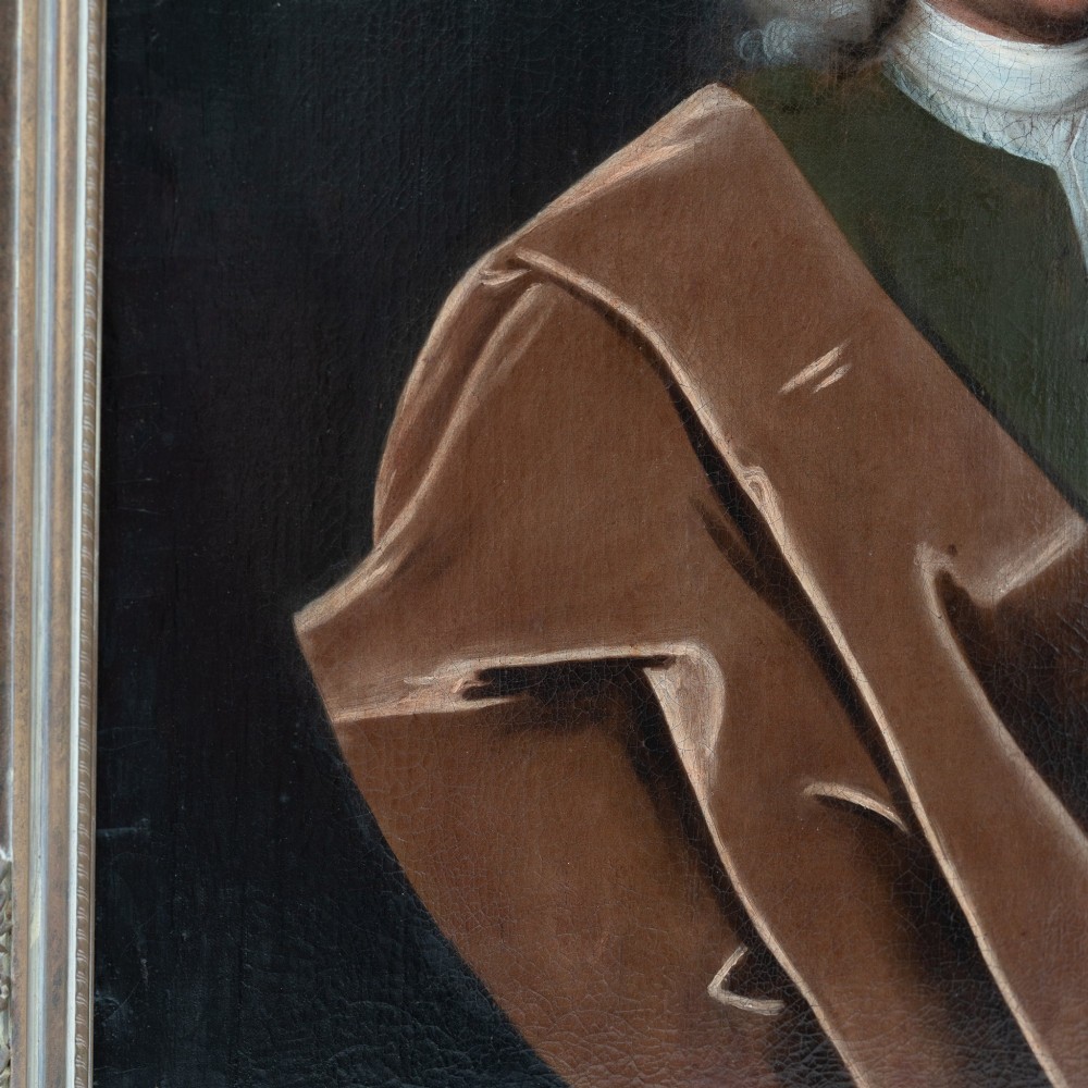 An 18th-century oil portrait on canvas depicting a gentleman in a powdered wig, white cravat, and draped brown mantle, presented in an ornate gilt frame. View V