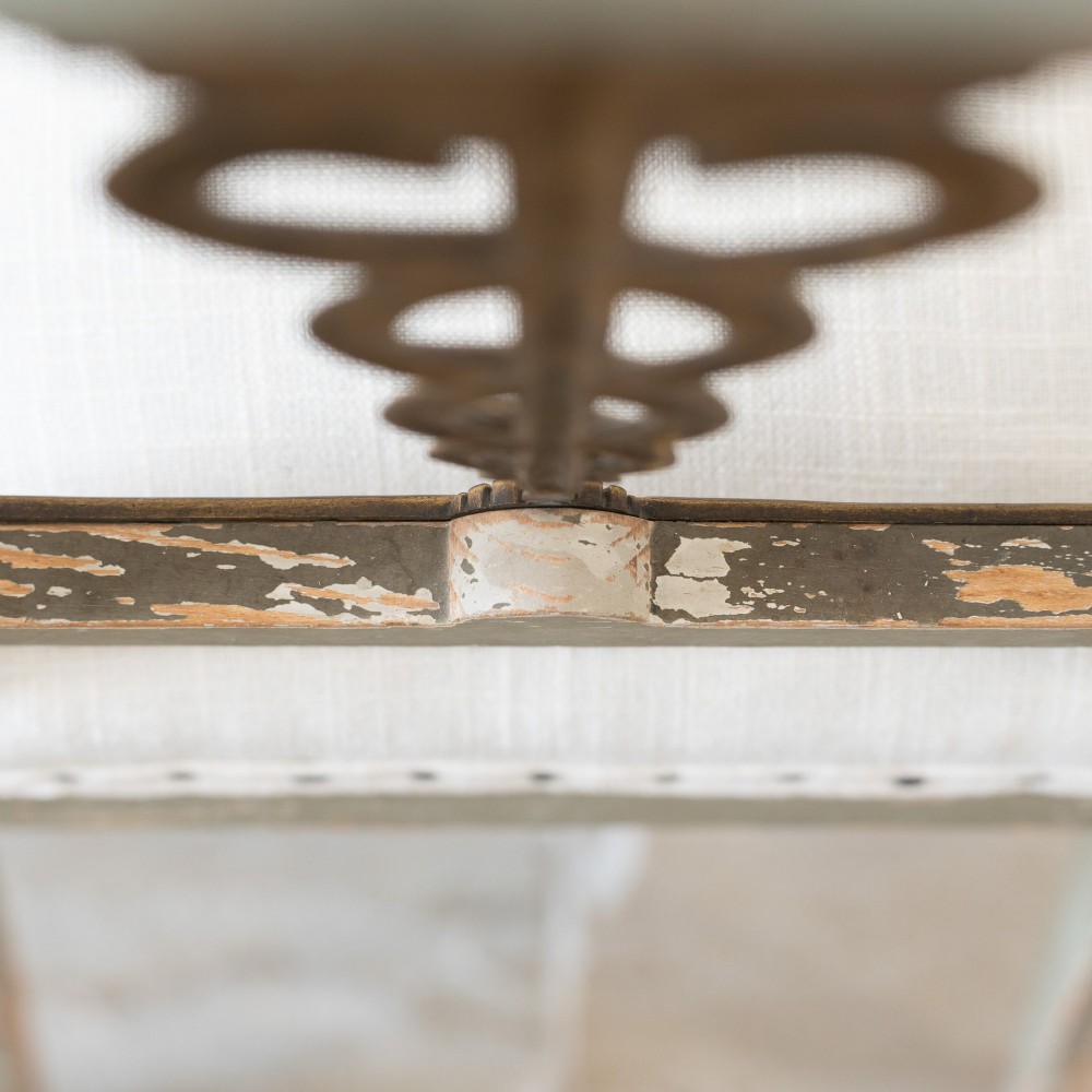 A set of four 19th-century Northern European Neoclassical side chairs featuring distressed grey paintwork, off-white linen upholstery, and gilded caduceus motifs in the open back frames. View IX